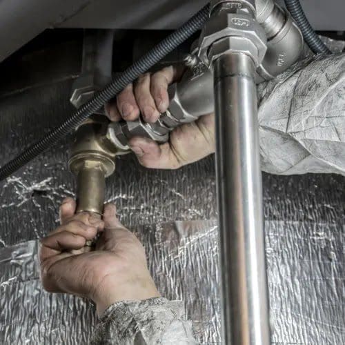 Pair of hands holding connecting water pipes together.